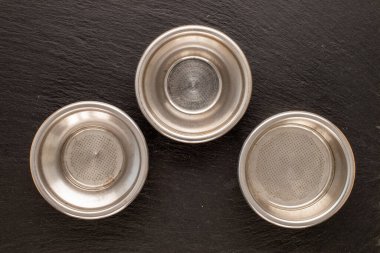 Bir kahve makinesine üç metal elek, bir taş, makro, üst manzara..