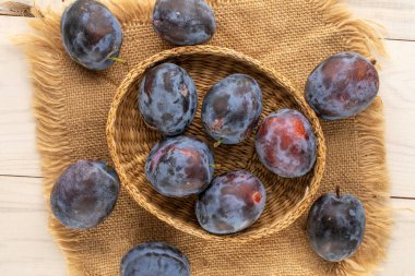 Birkaç organik erik, saman tabağı ve ahşap masa üzerinde jüt peçete, makro, üst manzara..