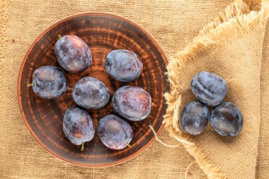Jüt kumaş, makro, üst manzara üzerinde kil plakalı bir sürü olgun erik..