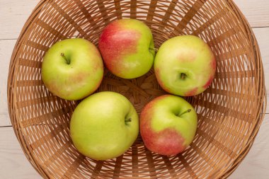 Tahta bir masa üzerinde saman plakalı birkaç yeşil elma, makro, üst görünüm.