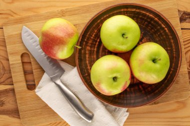 Kil plakalı birkaç yeşil elma ve ahşap masa üzerinde bıçak, makro, üst manzara.