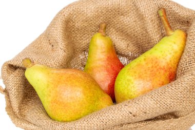 Üç organik yeşil armut, bir jüt çanta üzerinde, yakın plan, beyaz arka plan.