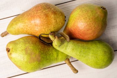 Dört olgun sulu armut, yakın plan, beyaz ahşap bir masanın üstünde, üst manzara..