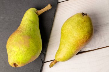 Tahta tahtası olan iki organik sulu armut, yakın plan, beyaz ahşap masa, üst görünüm..