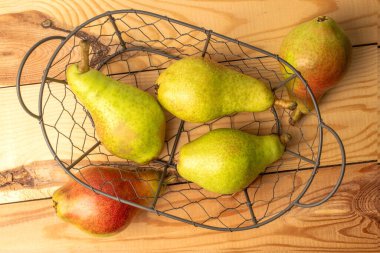 Metal sepetin içinde birkaç organik sulu armut, yakın plan, ahşap masa, üst görüş..