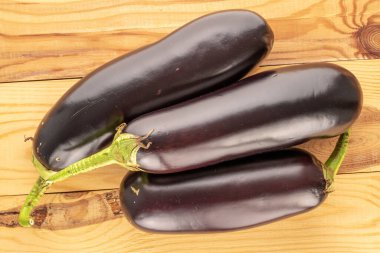 Tahta bir masada üç olgun patlıcan, makro, üst manzara..