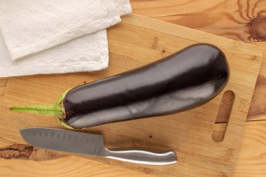 Olgun bir patlıcan, bambu kesme tahtası ve bıçakla ahşap masa, makro, üst manzara..