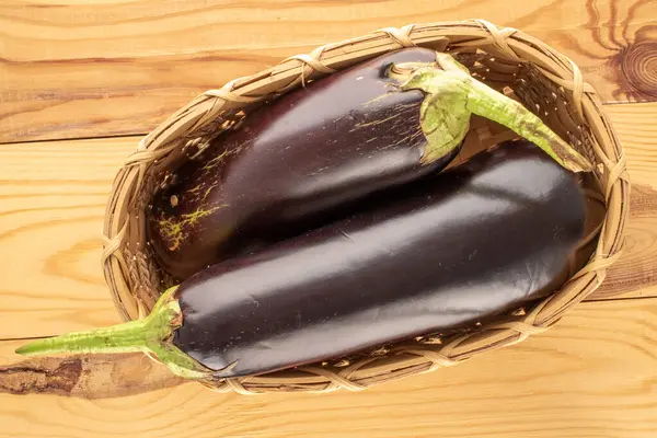 Tahta bir masada sepetin içinde iki olgun patlıcan, makro, üst manzara..