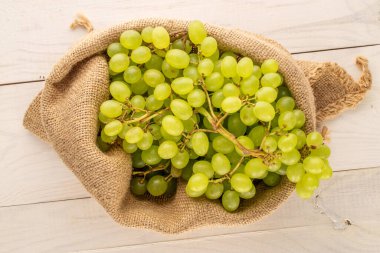 Tahta bir masanın üstünde, jüt çantasındaki organik üzümler, makro, üst manzara..