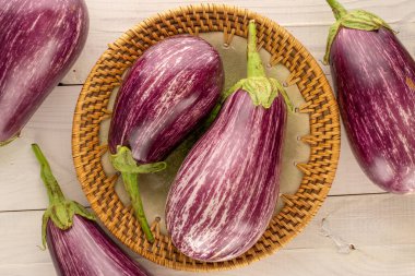 Tahta bir masanın üzerinde seramik tabakla, makroyla, üst manzaralı birkaç olgun patlıcan..