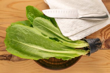 Taze yeşil salata yaprakları, kil tabağı ve bıçak, ahşap masa, makro, üst manzara..