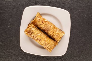 İki parça tatlı baklava, beyaz seramik çay tabağı, kayrak taşı, makro, üst manzara..