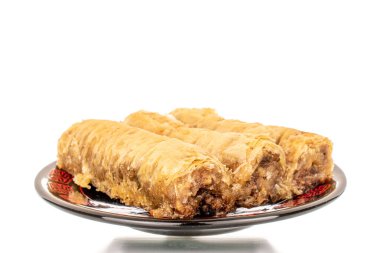 Seramik bir tabakta üç parça tatlı baklava, yakın plan, beyaz arka planda izole edilmiş..