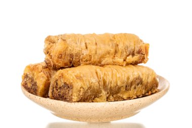 Seramik bir tabakta üç parça tatlı baklava, yakın plan, beyaz arka planda izole edilmiş..