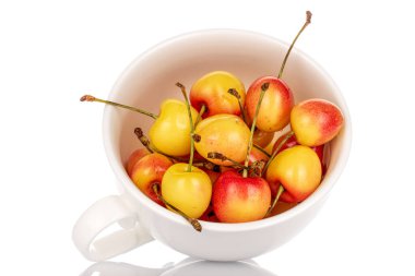 Beyaz bir seramik fincanda, beyaz arka planda izole edilmiş olgun, sarı kiraz meyveleri..