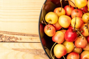 Tahta bir masanın üzerinde seramik tabakla birkaç kiraz çileği, makro, üst manzara..