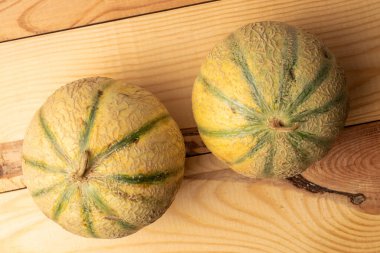 Üç güzel kokulu organik kavun, yakın planda, ahşap bir masada, üst tarafta..