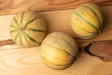 Üç güzel kokulu organik kavun, yakın planda, ahşap bir masada, üst tarafta..