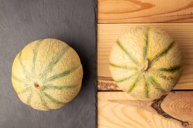 Servis tahtasındaki iki güzel kokulu organik kavun, yakın plan, ahşap masa, üst görüş..