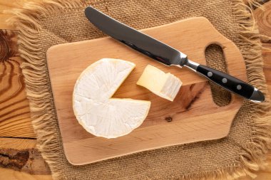 Ahşap mutfak tahtasındaki bıçakla kokulu brie peyniri, makro, üst manzara..