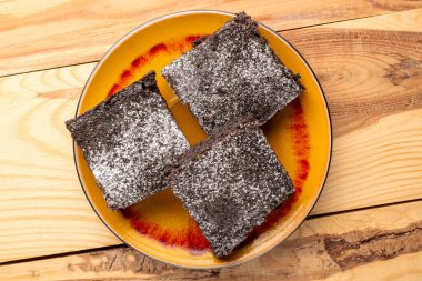 Üç parça klasik çikolatalı brownie, seramik tabak, ahşap masa, makro, üst manzara..