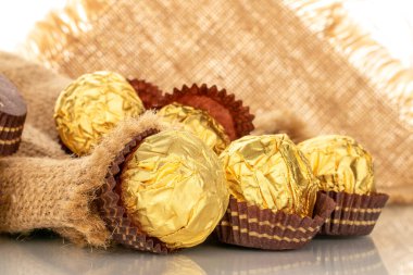 Kağıt ambalaj kağıdında fındıklı çikolatalı şekerler, yakın plan, beyaz arka planda izole edilmiş..