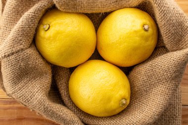 Çantanın içinde üç sarı olgun limon, yakın plan, üst manzara..