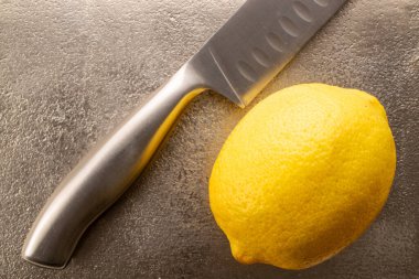 Bir sarı sulu limon, metal bir bıçakla tepside, yakın plan, üst görüş..