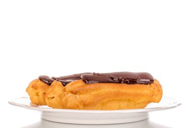 Beyaz seramik bir tabakta üç tane çikolatalı pasta, yakın plan, beyaz arka planda izole edilmiş..