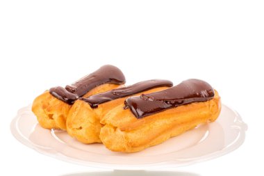 Beyaz seramik bir tabakta üç tane çikolatalı pasta, yakın plan, beyaz arka planda izole edilmiş..