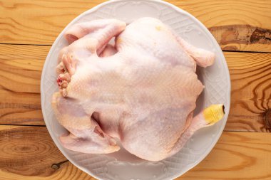 Ahşap bir masada seramik tabakta çiğ tavuk leşi, makro, üst manzara..