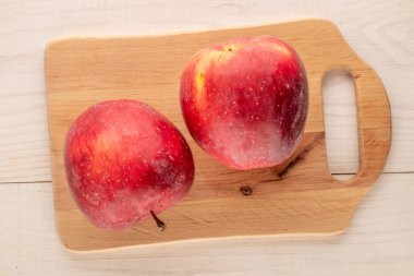 Tahta bir masanın üzerinde tahta kesme tahtası olan iki kırmızı elma, makro, üst manzara..