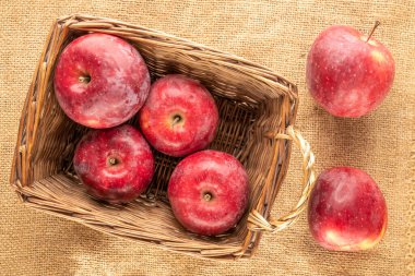 Bir sepetin içinde kırmızı elmalar, jüt kumaş, makro, üst manzara..
