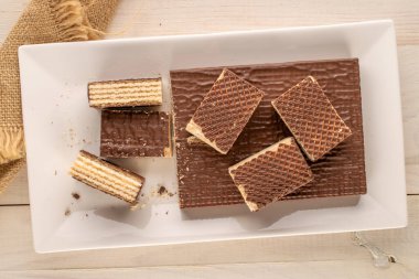 Tahta masa üzerinde seramik tabağı olan çikolatalı gofretler, makro, üst manzara..