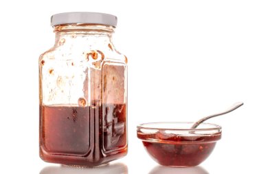 Cam kavanozda çilek reçeli ve cam bir fincan tabağında, makro, beyaz arka planda izole edilmiş..