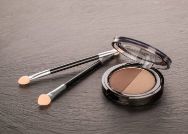 Göz farı ve kayrak taşı üzerinde iki kozmetik aplikatör..