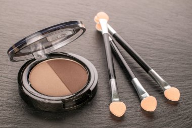 Göz farı ve kayrak taşı üzerinde üç kozmetik aplikatör, makro.