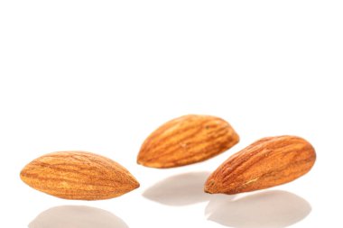 Birkaç kavrulmuş badem, makro, beyaz arka planda izole edilmiş..