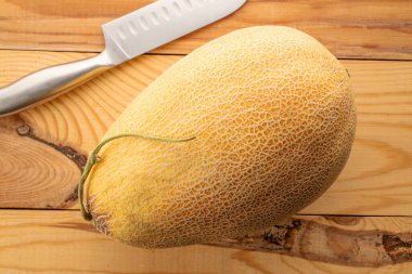 Tahta masada metal bıçaklı olgun bir kavun, makro, üst manzara..