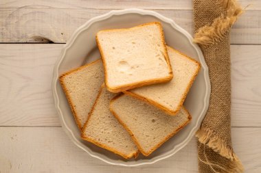 Ekmek kızartma makinesi için birkaç parça beyaz ekmek. Ahşap masa üzerinde seramik tabak, makro, üst görünüm..