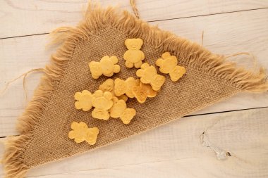 Tahta bir masanın üstünde jüt peçeteyle ayı şeklinde lezzetli kurabiyeler, üst manzara, makro.