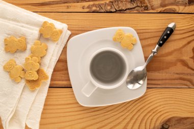 Tahta bir masada seramik tabakları olan ayı şeklinde lezzetli kurabiyeler, üst manzara, makro.