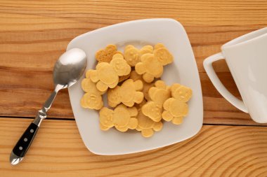 Tahta bir masada seramik tabakları olan ayı şeklinde lezzetli kurabiyeler, üst manzara, makro.