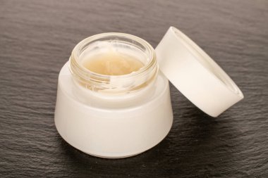 Bir cam kavanoz yüz kremi kayrak taşında.