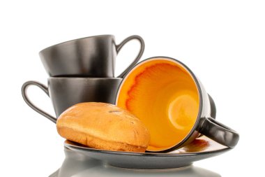 Beyaz arka planda izole edilmiş seramik fincanlar ve çay tabağı ile bir tatlı çörek..