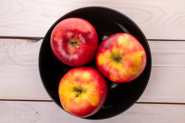 Tahta bir masada siyah plakalı üç kırmızı elma, makro, üst manzara..
