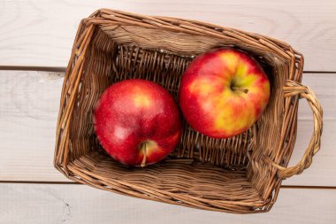 Tahta bir masada sepetli iki kırmızı elma, makro, üst manzara..