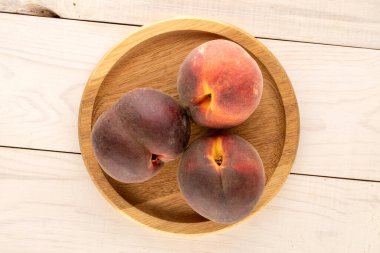 Üç olgun şeftali, ahşap bir tabakla, makro, üst manzara..