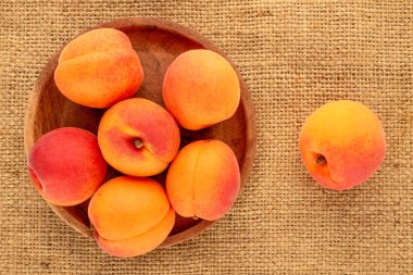 Jüt kumaş, makro, üst manzara üzerinde ahşap tabakla sulu kayısılar..