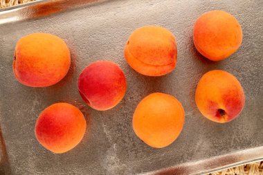 Saman hasırında metal tepsiyle sulu kayısılar, makrolar, üst manzara..